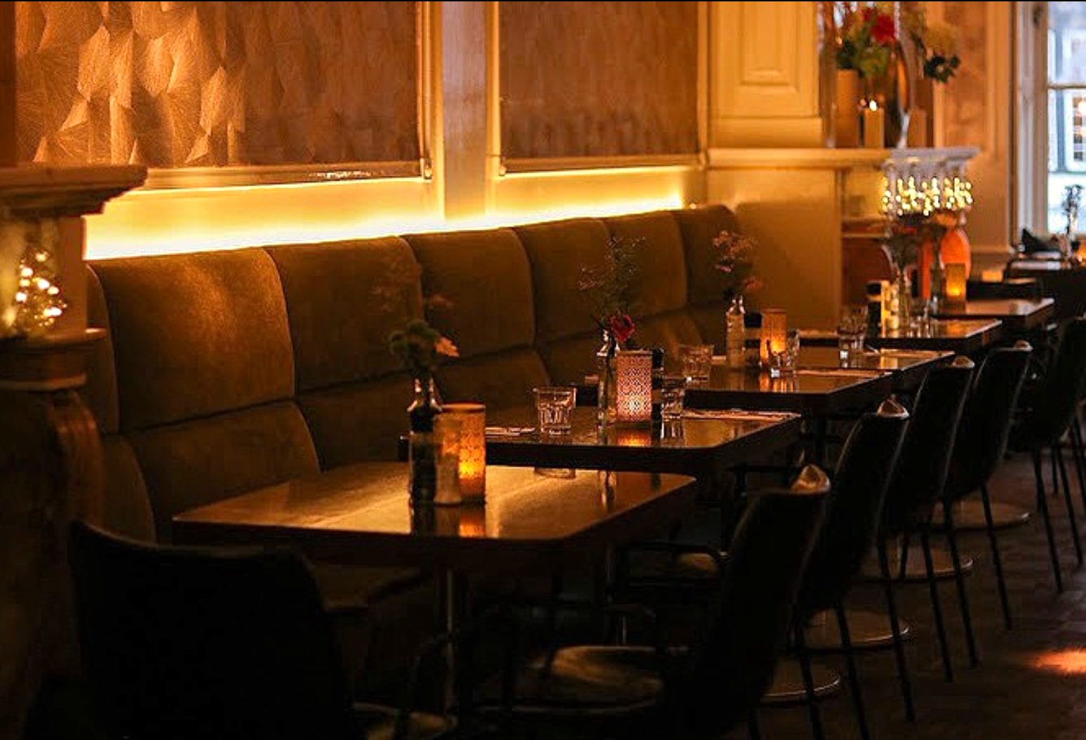 Het restaurant bij avond: groene banken, kaarslicht, uitzicht op de gracht